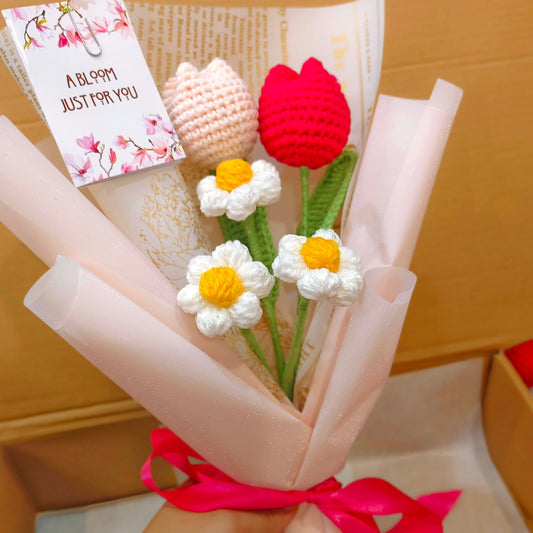 Knitted flower bouquet with a card on a wooden surface