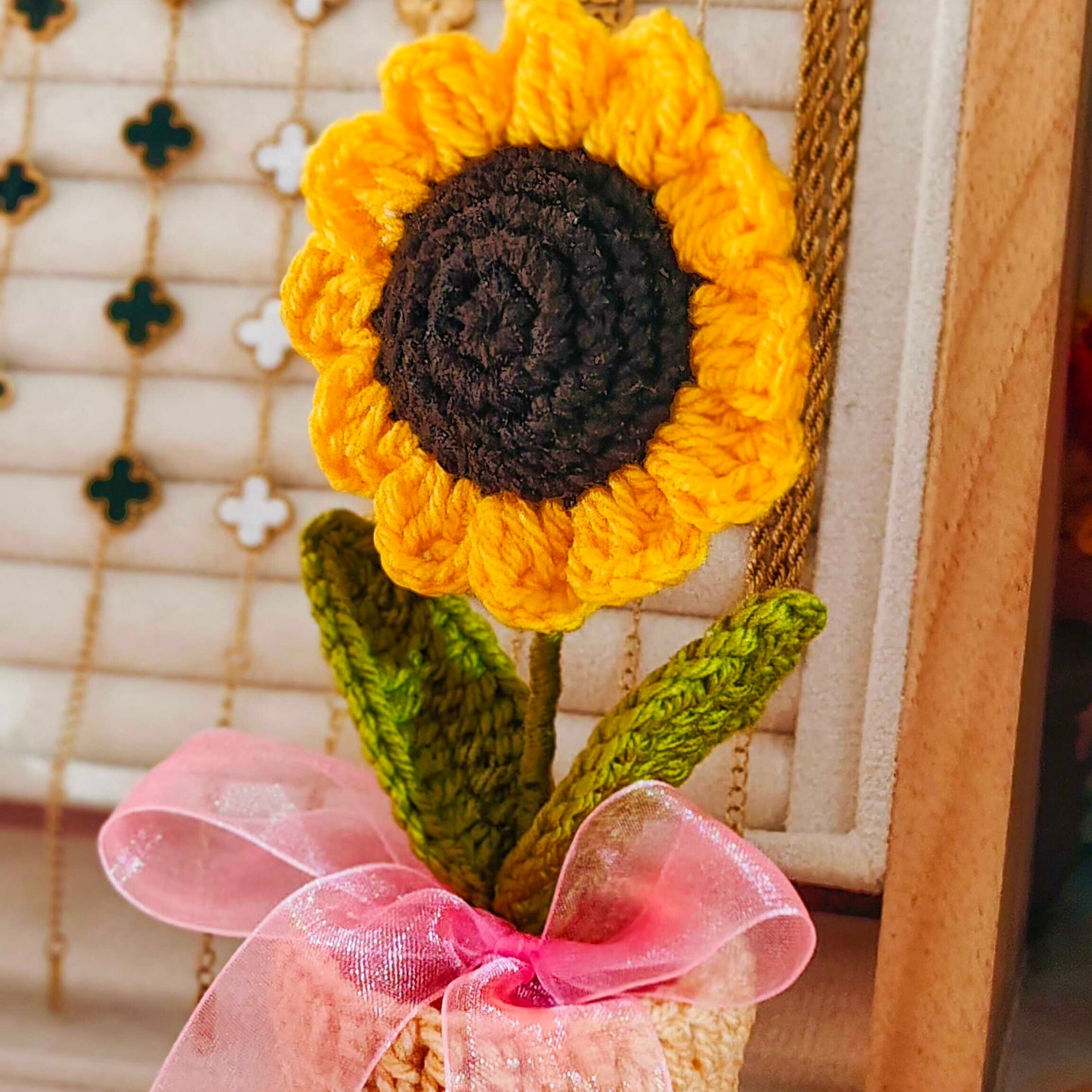 Crocheted sunflower with a pink ribbon on a neutral background
