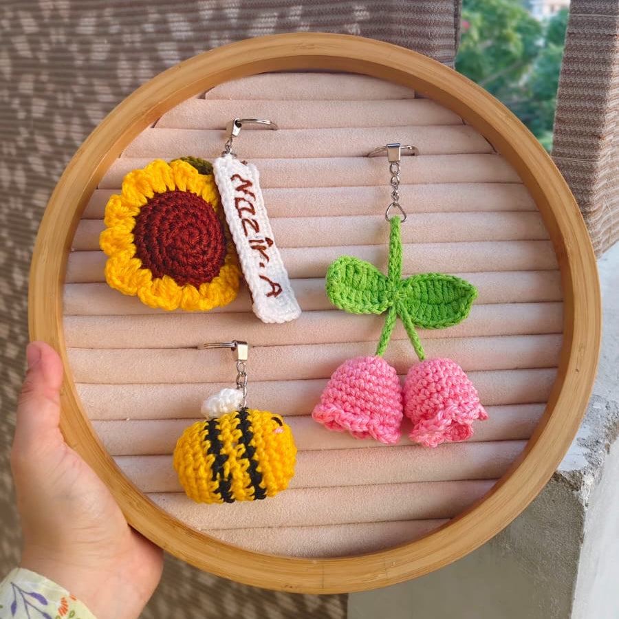 Handmade crochet earrings displayed on a wooden hoop with a blurred background
