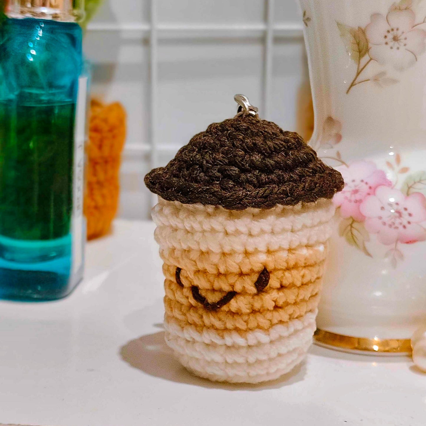 Crocheted cup with a brown lid on a white surface