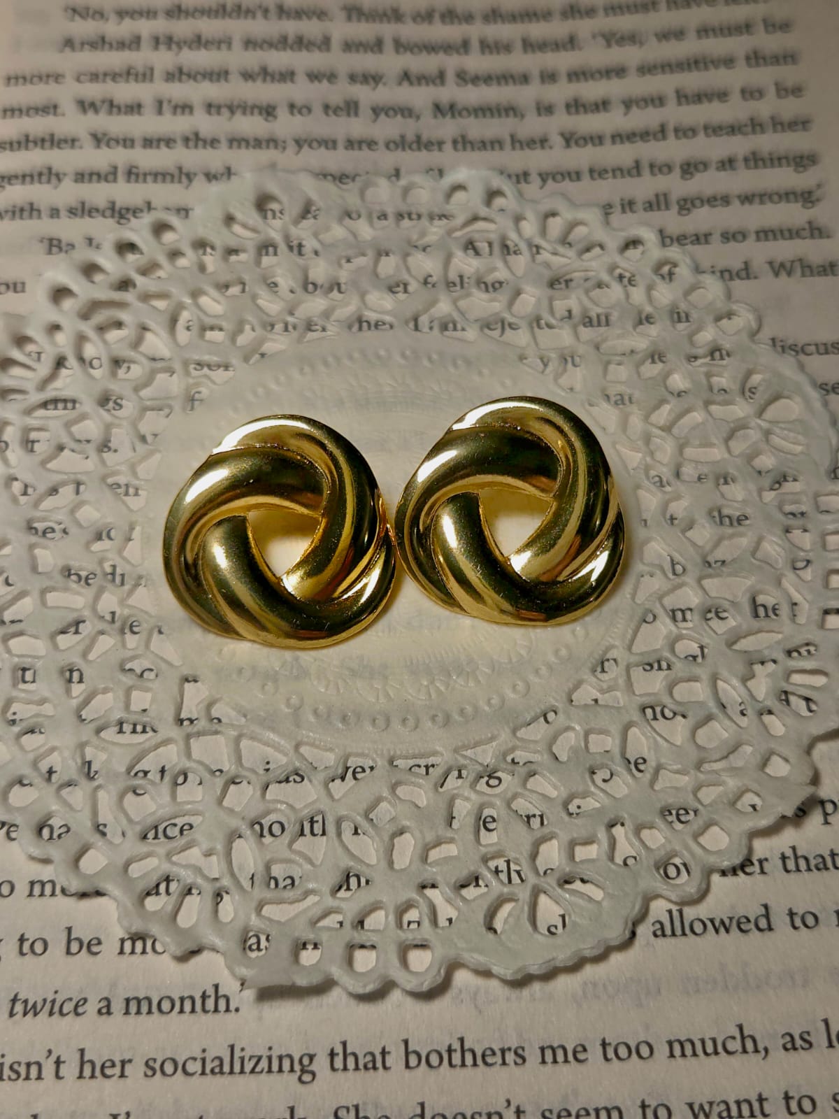 Gold knot earrings on a textured paper background