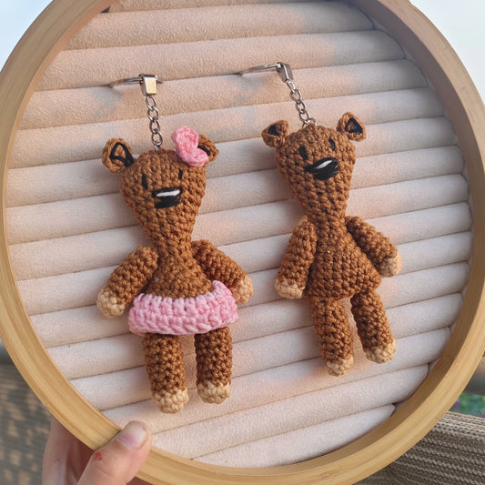 Two crochet teddy bear earrings on a wooden hoop with a light background