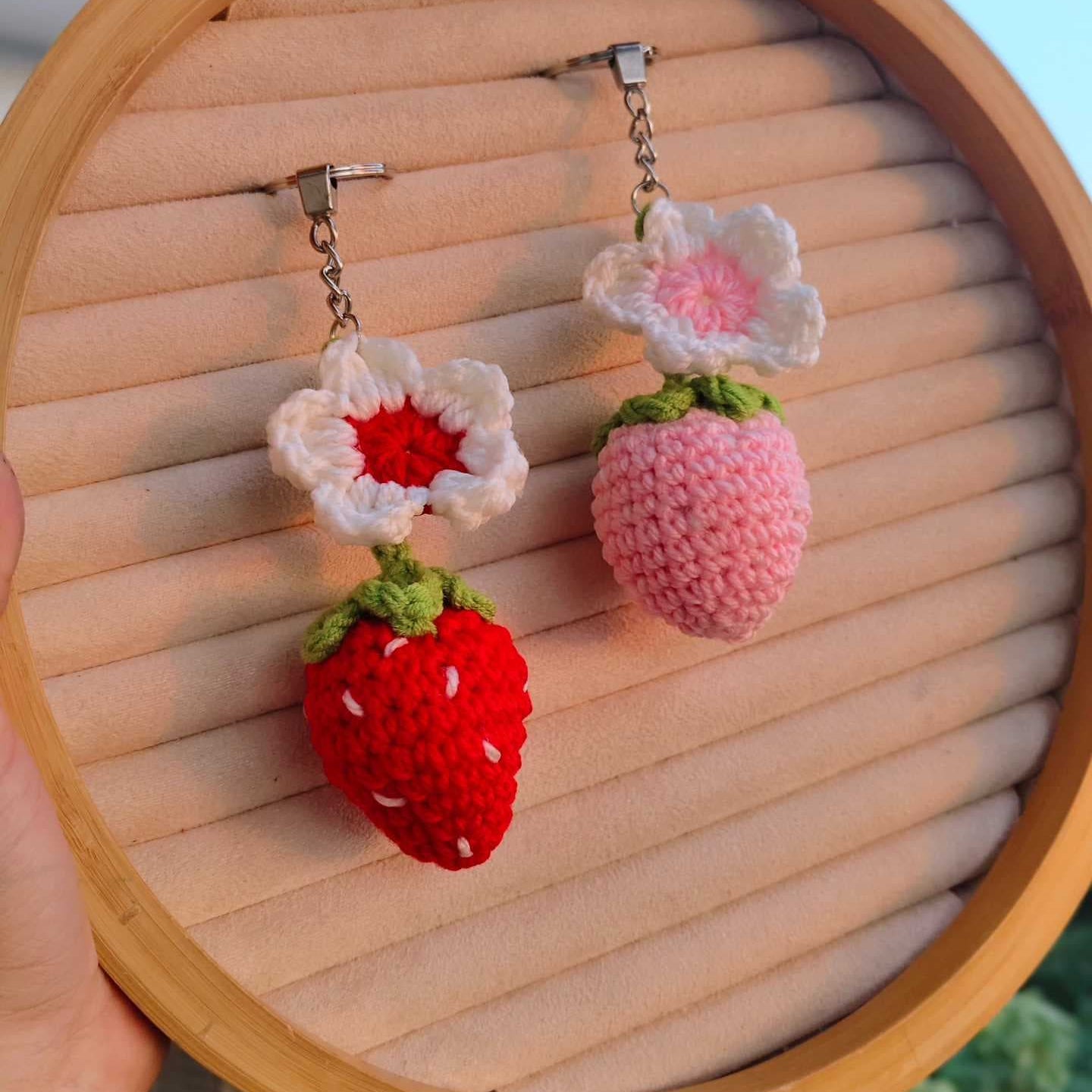 Handmade strawberry and flower earrings displayed on a wooden circular stand.