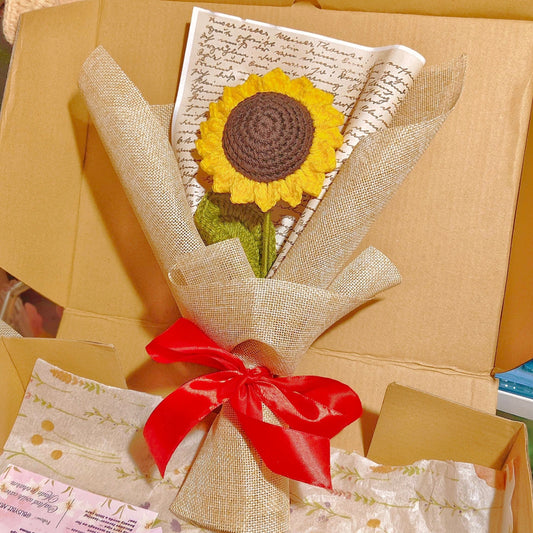 Gift wrapped with a sunflower-themed item and red ribbon, inside an open box.