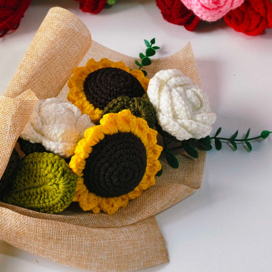 Bouquet of crocheted flowers including sunflowers and roses on a white background