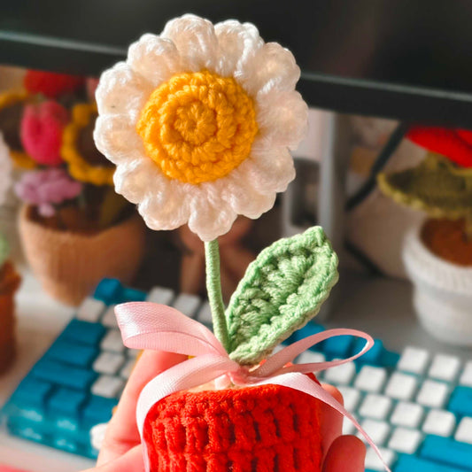 Handmade daisy flower in a pot held in front of a keyboard