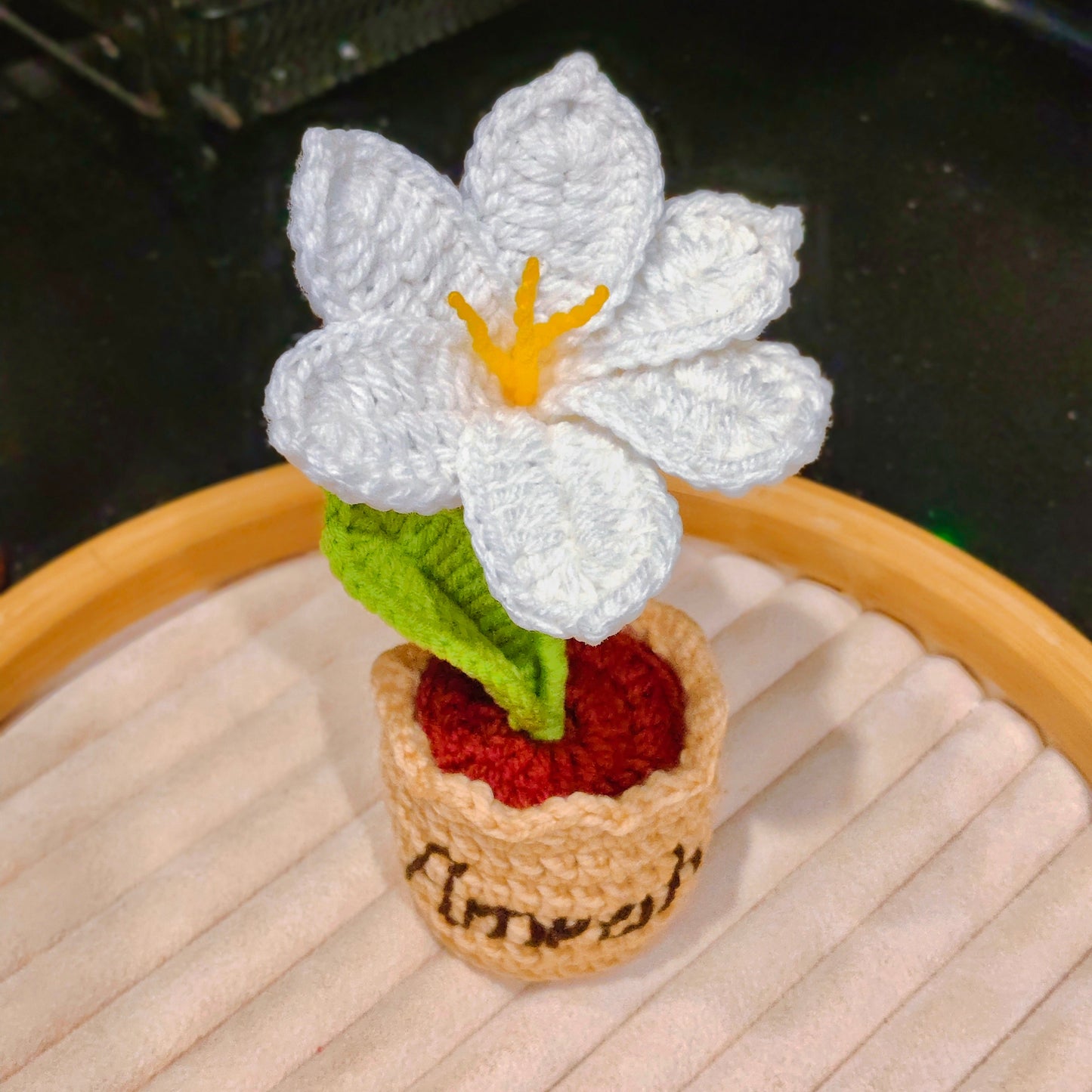 Crocheted white flower with a yellow center on a wooden surface.