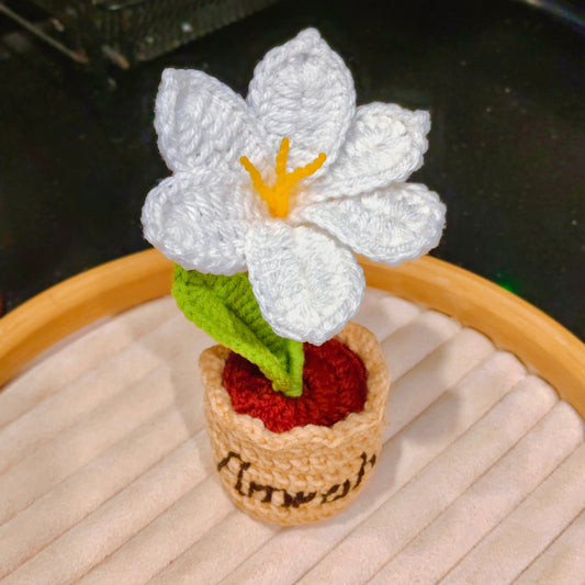 Crocheted white flower with a yellow center on a wooden surface.