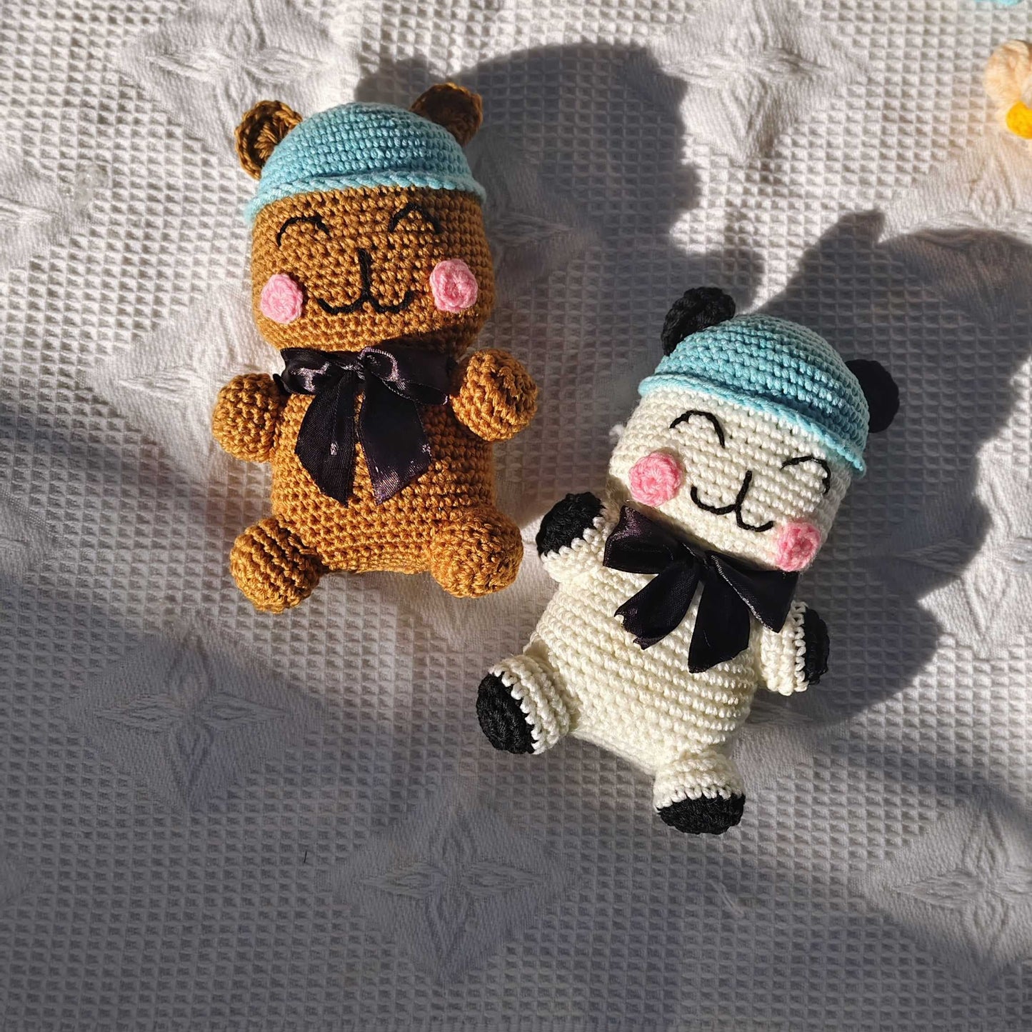 Two small crocheted animals wearing hats on a textured fabric background