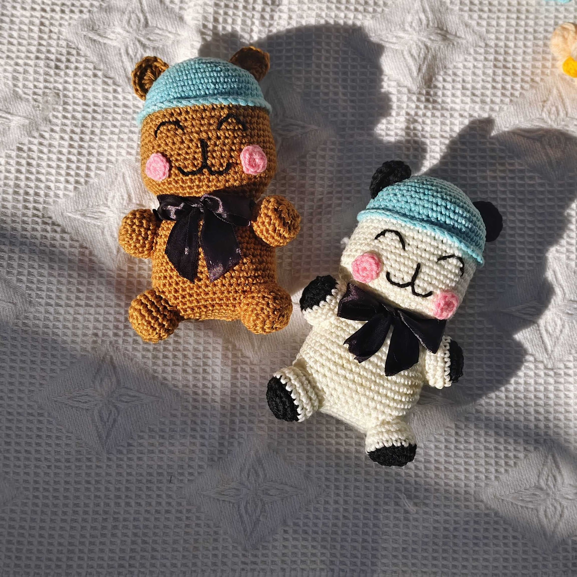 Two small crocheted animals wearing hats on a textured fabric background