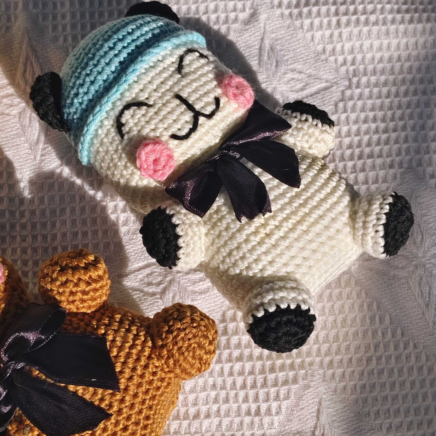 Two crocheted toys, one brown and one white with black accents, on a textured white surface.