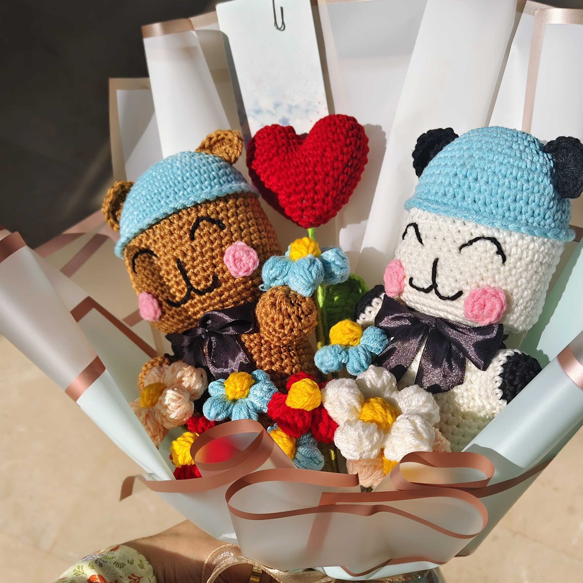 Bouquet of crochet dolls with a heart and flowers, held by a person.
