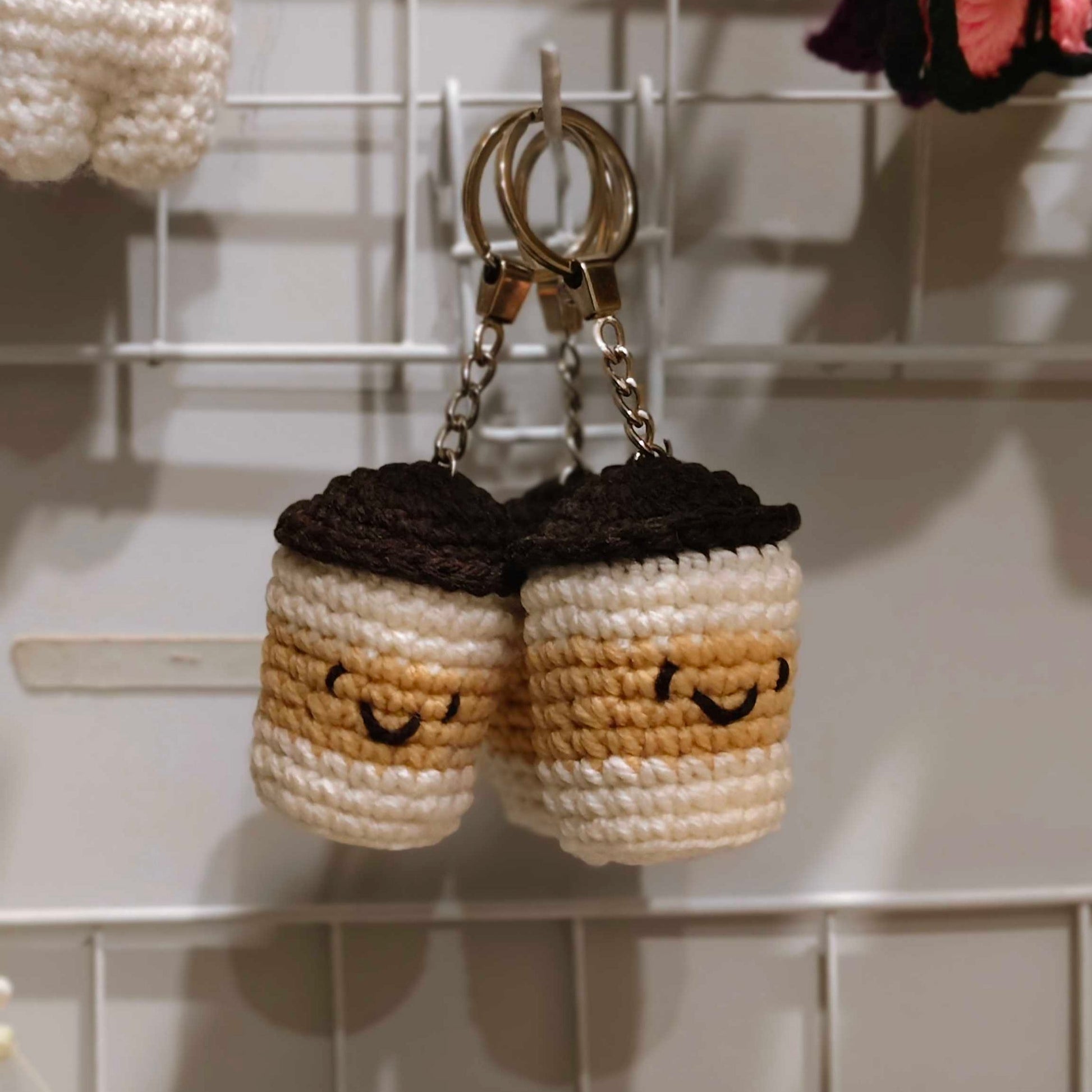 Two crocheted keychains shaped like donuts with faces on a white grid background.