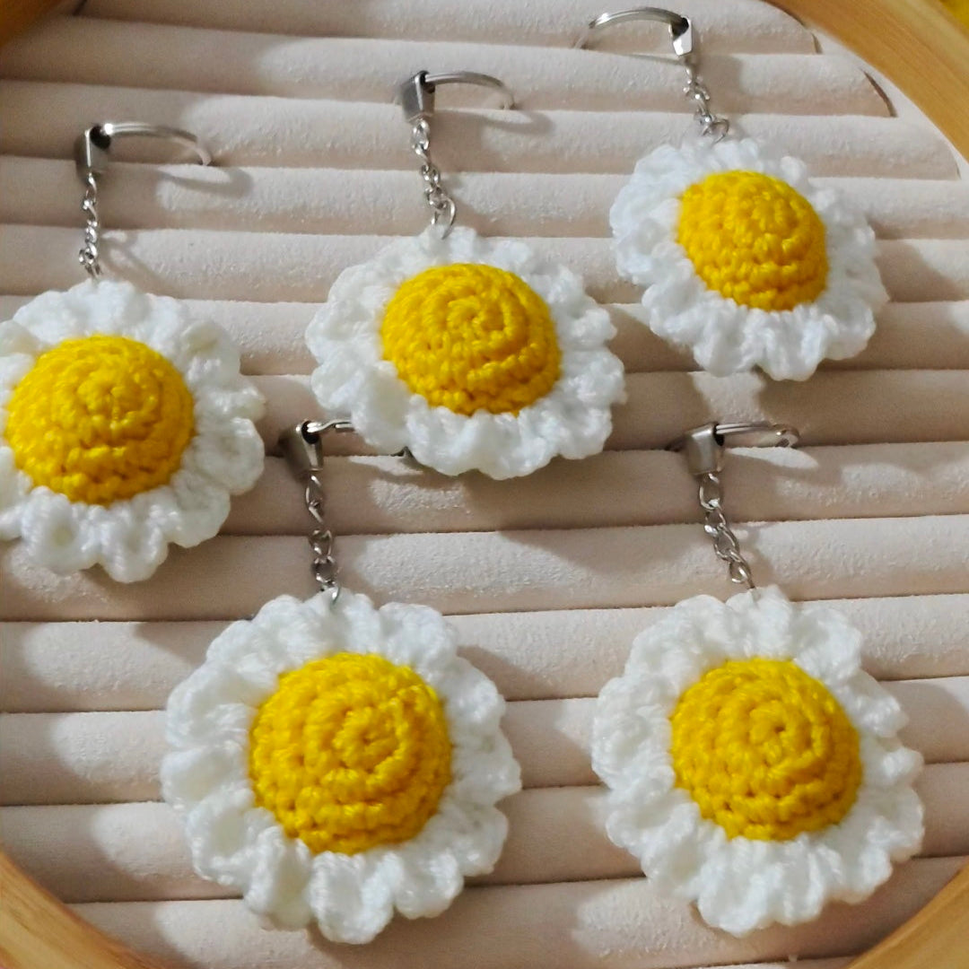 Crocheted daisy earrings on a wooden display board.