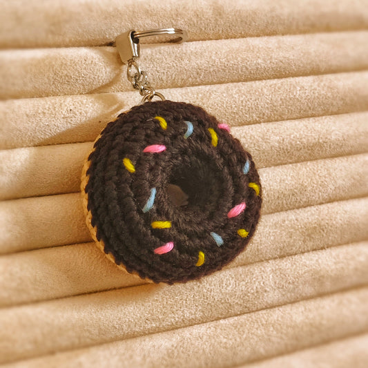 Donut-shaped keychain with colorful sprinkles on a beige textured background