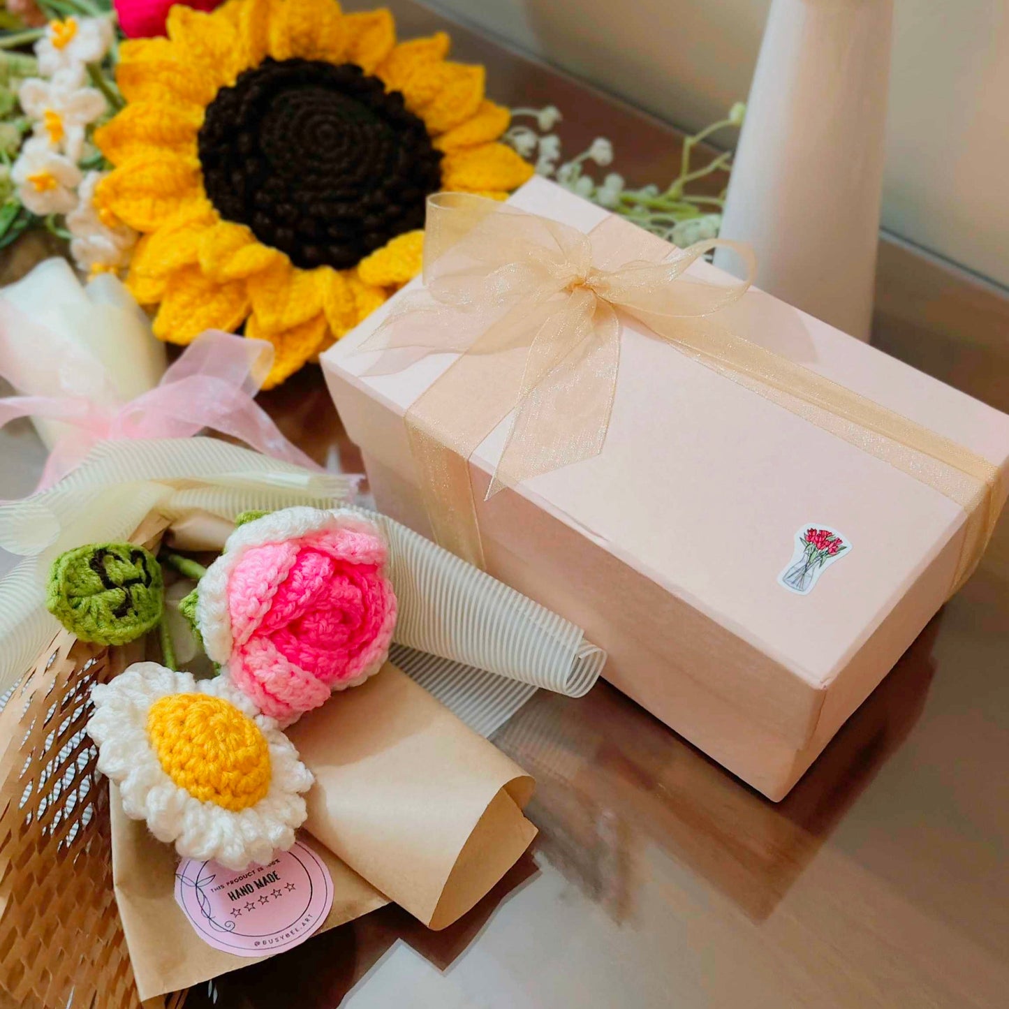 Gift box with decorative flowers and a sunflower on a reflective surface