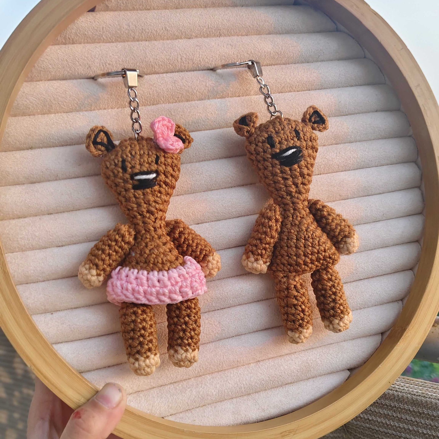 Two crochet teddy bear earrings on a wooden hoop with a light background