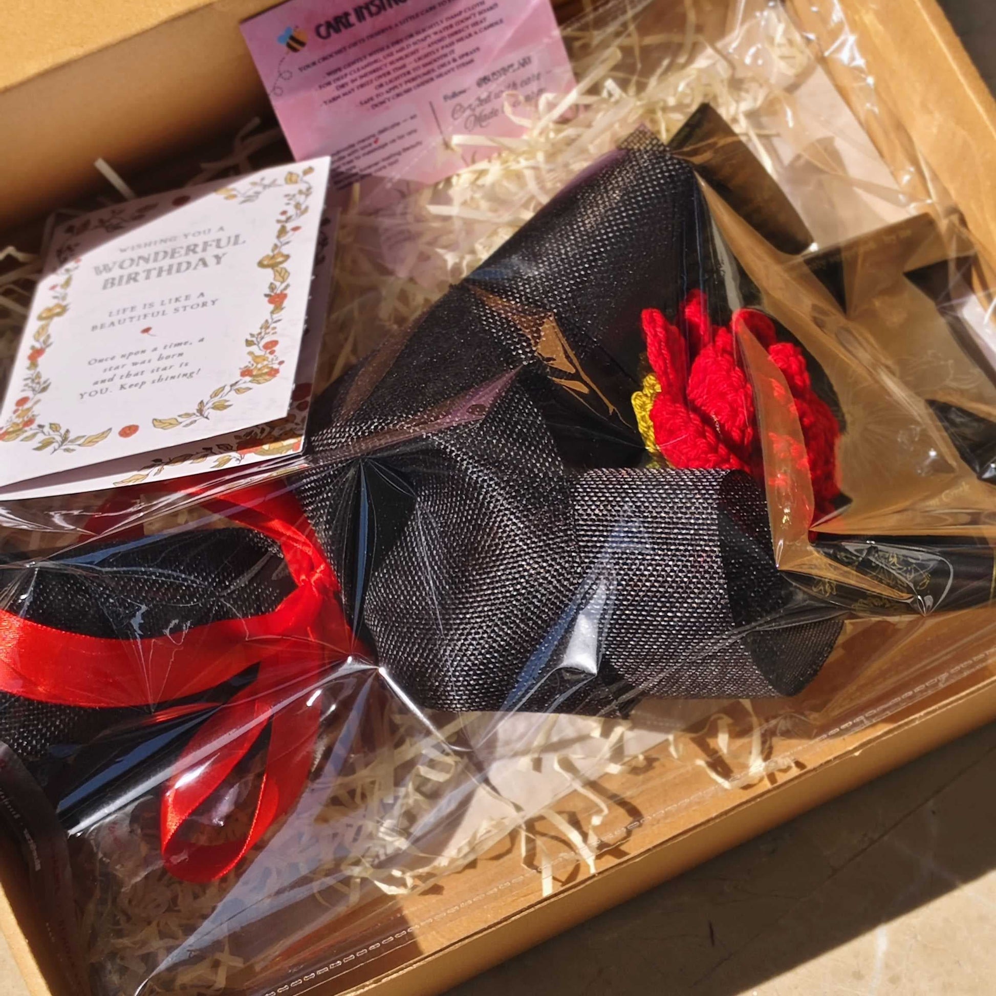 Box containing a black hat with red accents and other items on a beige surface