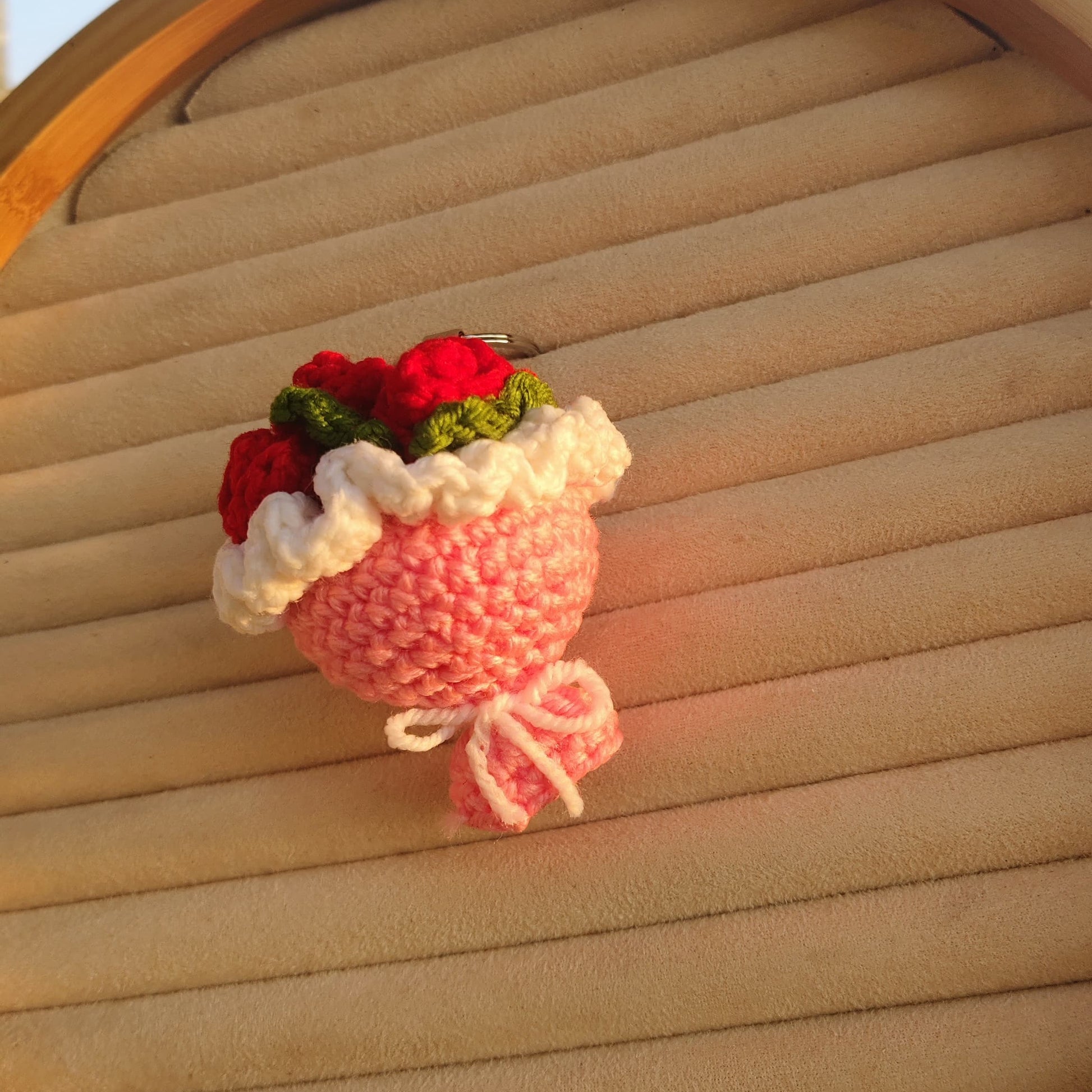 Crocheted flower pot with red flowers on a woven surface