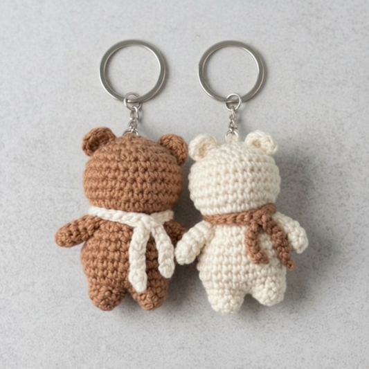 Two crochet keychains shaped like bears with scarves on a light gray background