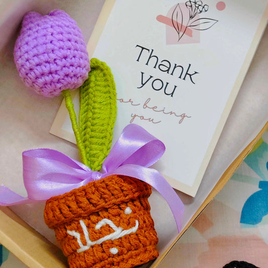 Crocheted tulip with a card that says 'Thank you for being you' on a floral-patterned background.