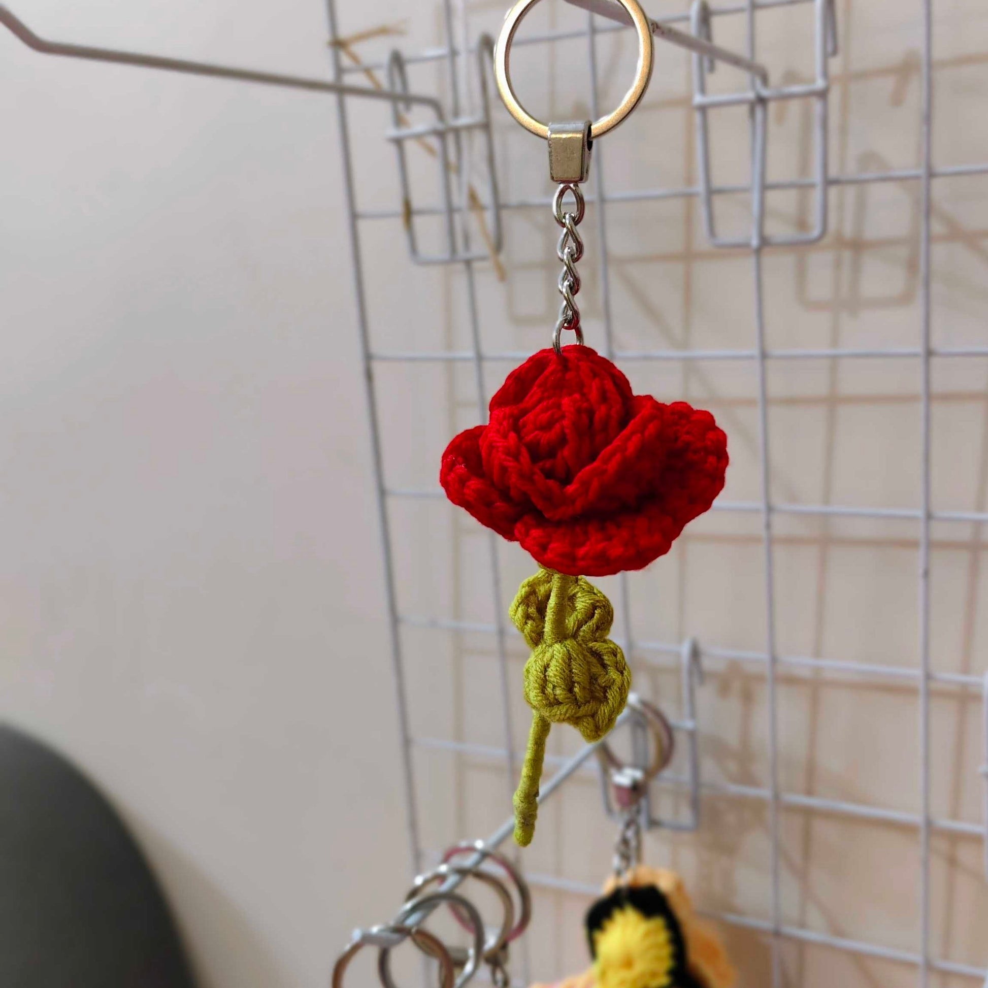 Red crocheted flower keychain with a yellow butterfly on a metal hook.