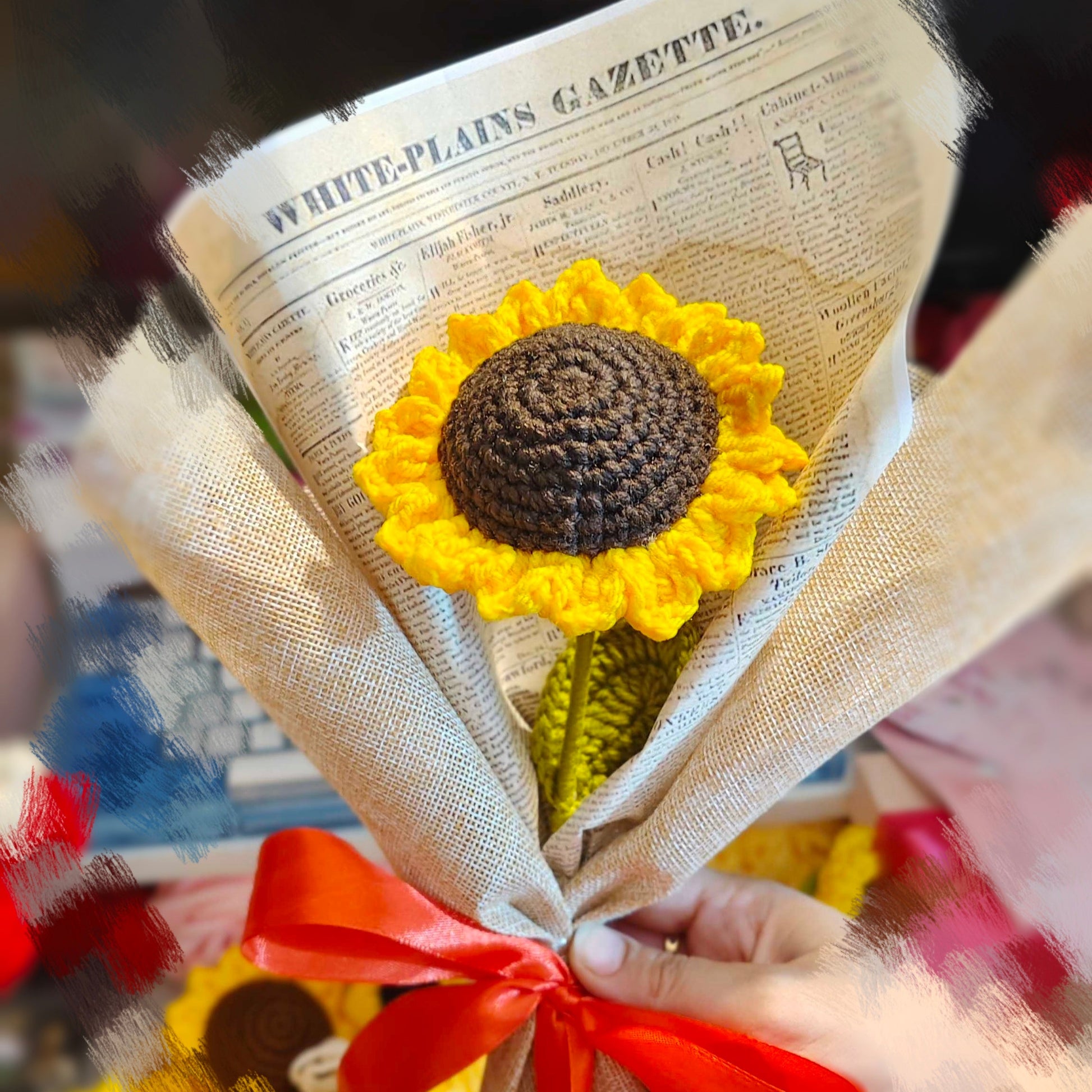 Bouquet of sunflower-shaped crocheted flowers with a red ribbon on a newspaper background.